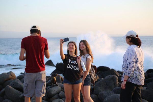 Adolescent girls taking a picture on Galapagos Islands' shore.